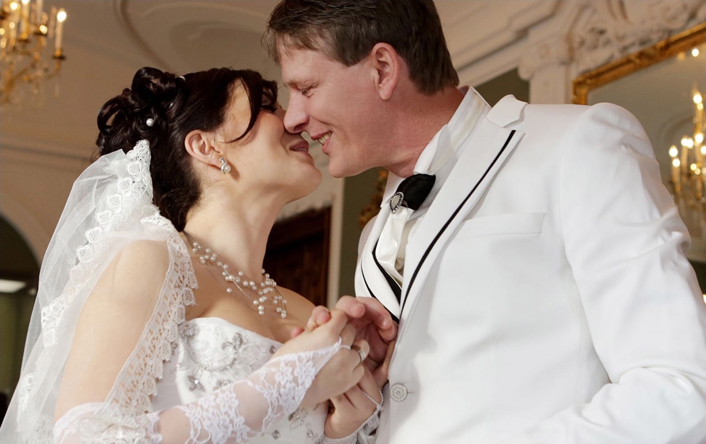 Der erste offizielle Kuss einen Brautpaares an den Händen haltend während der Trauzeremonie